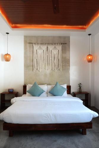 a bedroom with a large white bed with blue pillows at The Hide El Nido Villas in El Nido