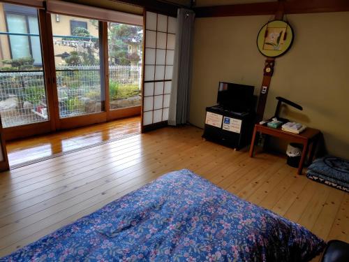 a room with a bed and a wooden floor with a window at 町中ステイ 宗ハウス in Nachikatsuura