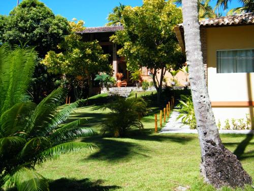 a house with a palm tree in front of a yard at Igarakuê Flat in Japaratinga