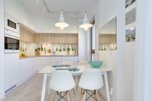 a white kitchen with a table and two white chairs at Apartament Dani-Apart in Gdańsk