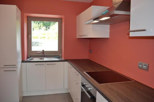 a kitchen with white cabinets and a window at Gîtes Paquay in Libramont