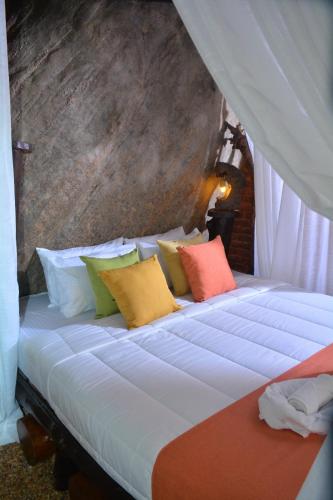 a bed with colorful pillows on it in a room at Giripura Resort - Kandy in Kandy