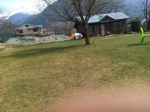 a green bench in a yard with a tree at Golf view resort in Pahalgām