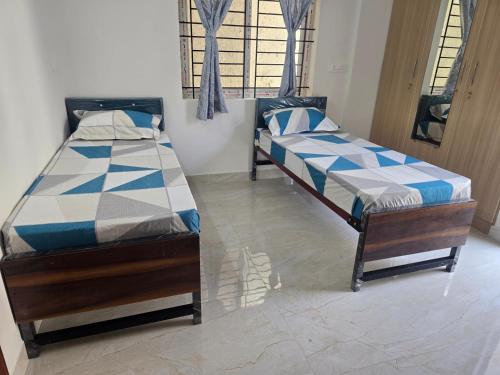 two twin beds in a room with a window at Om Sai Ram Coliving in Bangalore