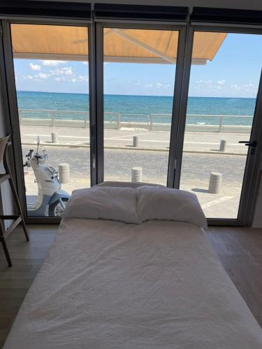 a bedroom with a bed and a view of the ocean at Seafront Home in Larnaca