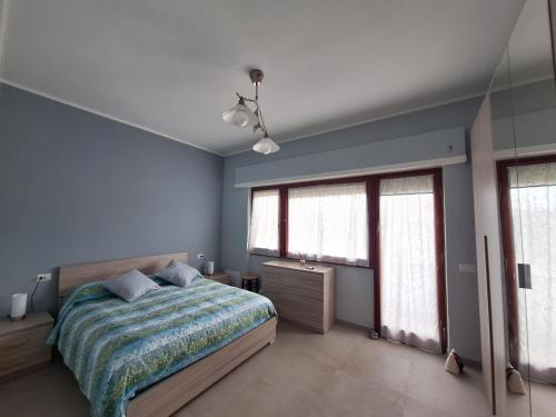 a bedroom with blue walls and a bed and windows at My Sunset in Torvaianica