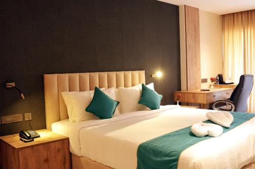 a bedroom with a large bed with green and white pillows at Hotel Searock in Trivandrum