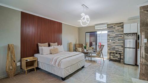 a bedroom with a bed and a table and a kitchen at DonDave Guesthouse in Rustenburg