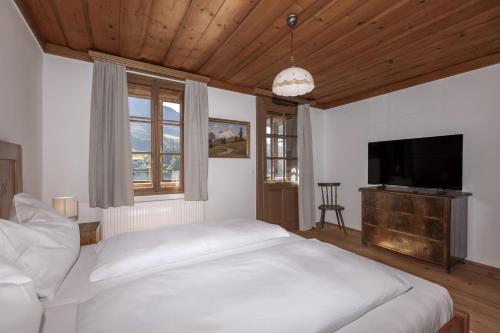a bedroom with a white bed and a flat screen tv at Haus Grundlseeblick in Bräuhof