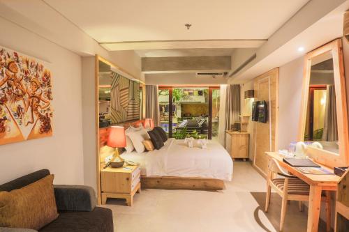 a bedroom with a bed and a desk with a desk at Serela Legian by KAGUM Hotels in Legian