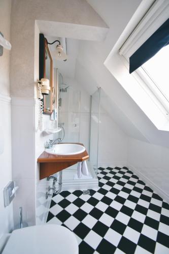 a bathroom with a sink and a black and white checkered floor at AKZENT Hotel Franziskaner in Dettelbach