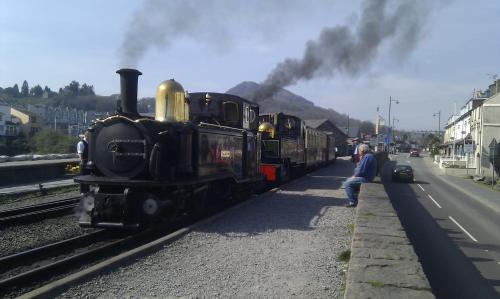 a man standing next to a train on the tracks at Estuary Lodge Motel B&B in Talsarnau