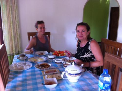 two women sitting at a table with food at Bee Nest Bed & Breakfast in Negombo