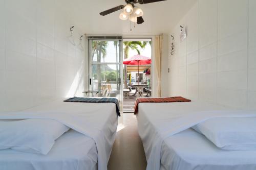 two beds in a room with a view of a patio at Hanamuro Inn Aka Island in Zamami