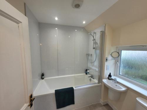 a bathroom with a shower and a tub and a sink at Riverside Home Kinlochleven in Kinlochleven