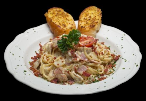 a white plate of pasta with bread and toast at I Rovers in Pattaya