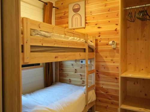 a bedroom with two bunk beds in a log cabin at Tiny Twins - TinyHouse 6 personnes à Malmedy by LaConciergerie in Malmedy