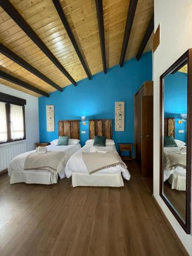 two beds in a room with blue walls and wooden ceilings at Casa del Tío Marcelo in Pedraza-Segovia