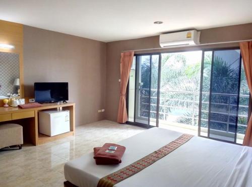 a bedroom with a bed and a desk and a television at Pearl Place Hotel in Hat Yai