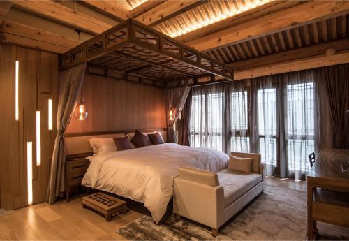 een slaapkamer met een groot bed in een kamer met ramen bij Cours Et Pavillons in Beijing