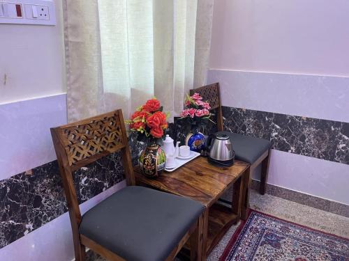a wooden table with two chairs and flowers on it at Hotel Srinivas in Jodhpur