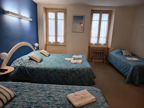 a room with three beds with towels on them at Hôtel restaurant Notre Dame in Orcival