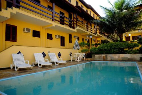 um hotel com piscina e cadeiras e um edifício em Hotel da Ilha em Ilhabela