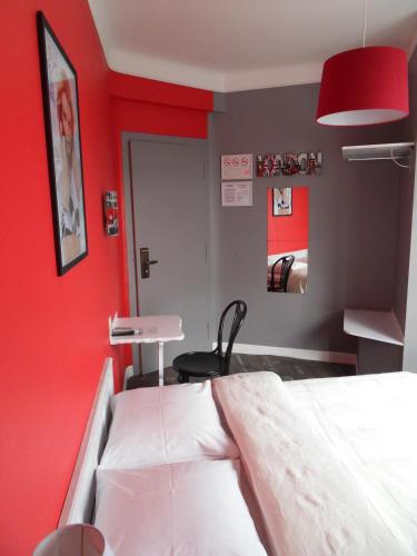 a room with a bed and a red wall at Hotel Du Centre in Hagondange