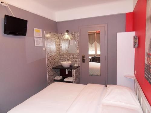 a bedroom with a bed and a small bathroom at Hotel Du Centre in Hagondange