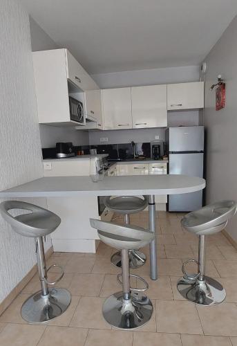 a kitchen with a white counter and stools in it at A 2 pas du port, du centre, du marché provençal, des plages quartier calme in Sanary-sur-Mer