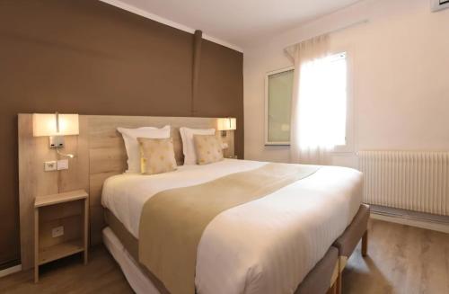 a bedroom with a large white bed and a window at Hôtel Archipel in Balaruc-les-Bains