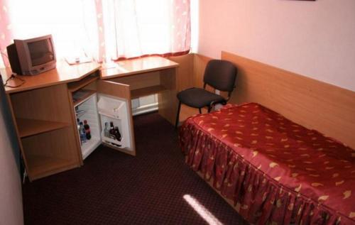 a hotel room with a bed and a desk and a television at Zhovtnevyi in Vinnytsya