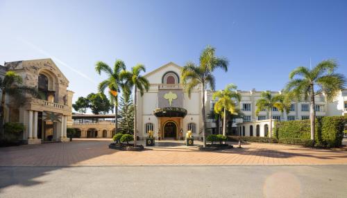 a large building with palm trees in front of it at Erawan Phangnga Hotel, Natai Beach in Ban Na Phong