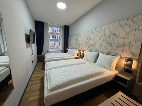a hotel room with three beds and a tv at Nivara Hotel in Hamburg