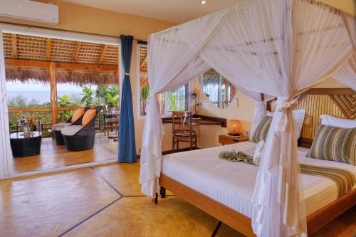 a bedroom with a canopy bed and a balcony at VILLA PANORAMA NOSY BE in Nosy Be