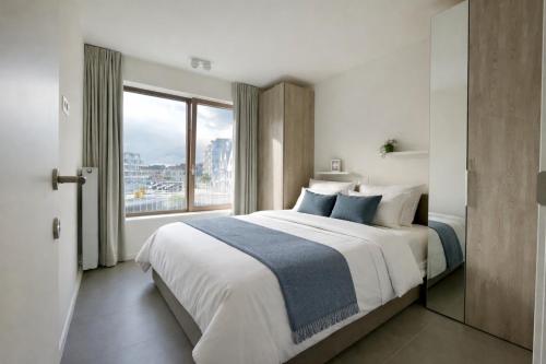 a bedroom with a large bed with a large window at West Bay Apartments in Middelkerke