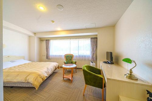 a bedroom with a bed and a desk with a television at ホテルマルセイユ in Shimoda