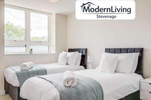 two beds in a bedroom with white sheets and white pillows at ModernLiving Stevenage 2 Bedroom Apartment Town Centre Sleeps 8 in Stevenage