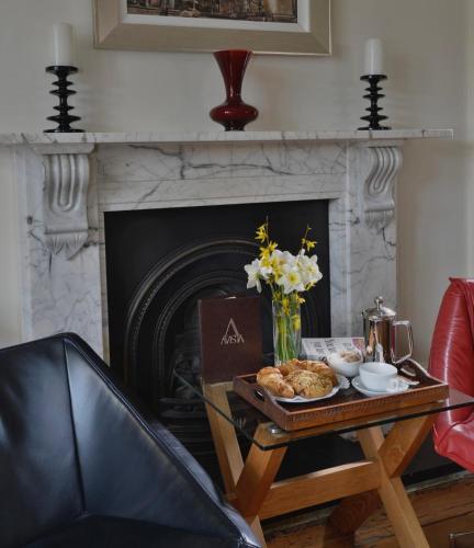 a living room with a table with a fireplace at Taunton House Hotel in Taunton