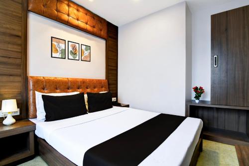 a bedroom with a large white bed with a wooden headboard at Super Hotel O Tagore Park Laskarhat Formerly Shankar Guest House in Kolkata