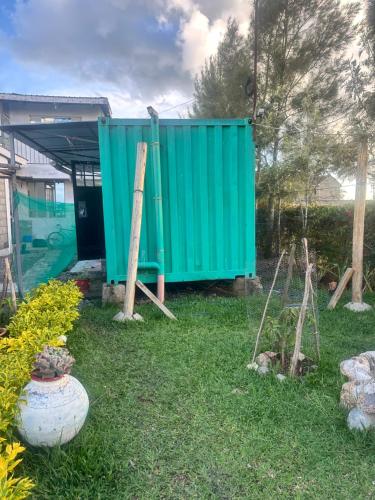 a green dumpster in a yard next to a house at Brighton court in Jomo Kenyatta Airport Nairobi