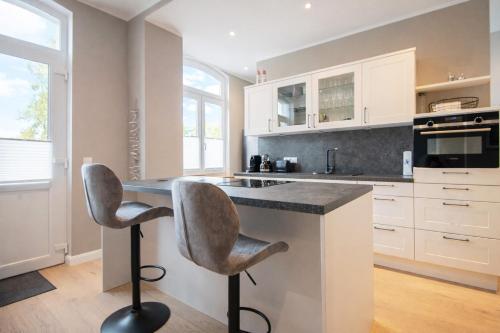 a kitchen with white cabinets and a counter with two stools at Inselrose in Juist
