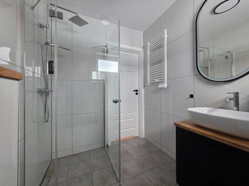 a bathroom with a glass shower and a sink at Zatoka Warmii in Tomaszkowo