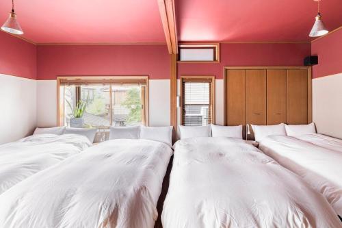 three beds in a room with red walls at BLIKIYA Doma in Fujiyoshida