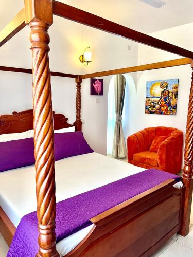a bedroom with a four poster bed and a couch at Magenta Apartment in Diani Beach