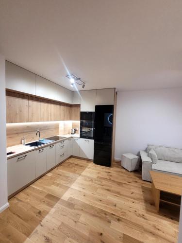 a kitchen with white cabinets and a black refrigerator at Apartament Lubawka in Lubawa