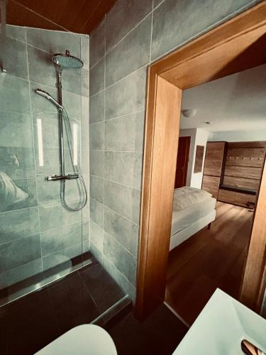 a bathroom with a shower and a bedroom with a bed at Hotel Tannenhof in Egmating
