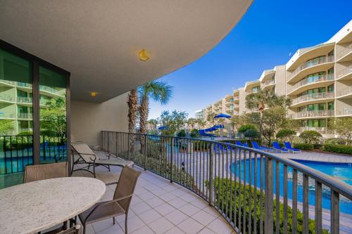 a balcony with tables and chairs and a swimming pool at Phoenix on the Bay 1124 in Orange Beach