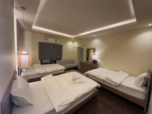 a room with two beds and a flat screen tv at Liwa sunrise Farm in Liwa