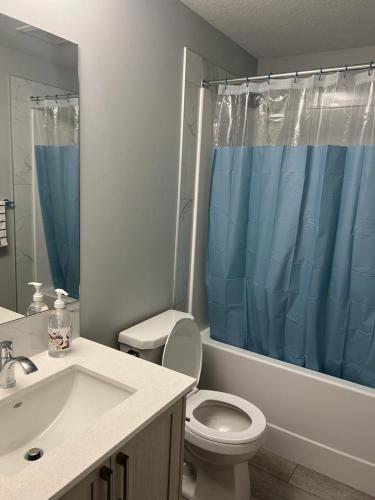 a bathroom with a toilet and a blue shower curtain at Authentic Suite in YYC